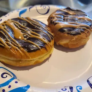two glazed donuts on a paper plate