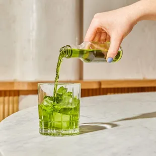 a person pouring a drink into a glass