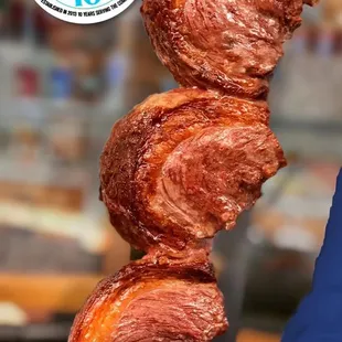 a person holding a skewer of meat