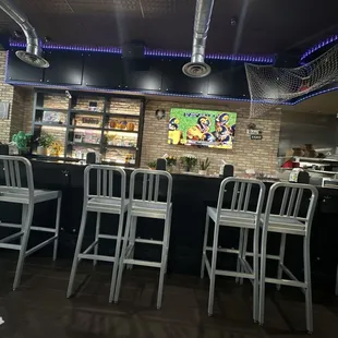 a bar with white chairs and a brick wall