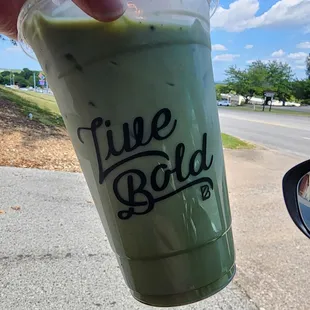 a hand holding a cup of green tea