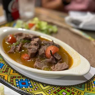 a bowl of stew with a side of bread