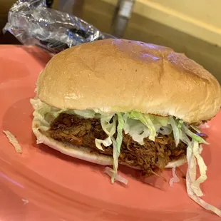 a pulled pork sandwich on a pink plate