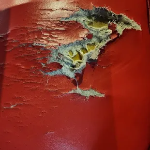 a red leather couch with peeling paint