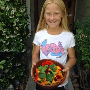 a young girl holding a bowl of vegetables