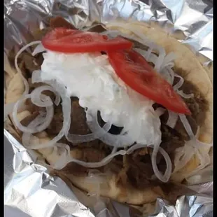 a close up of a pita with onions and tomatoes