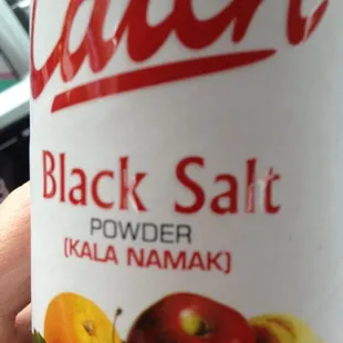 a hand holding a can of black salt