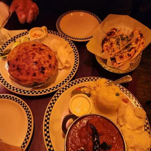 Upper left: lamb biryani with baked-on bread covering Upper right: garlic naan Below: Goan pork vindaloo