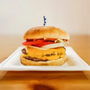 a hamburger with cheese, tomato and onion