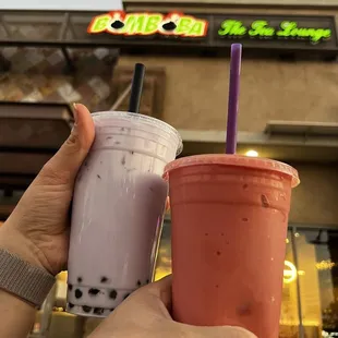 two cups of bubble tea in front of a donut shop