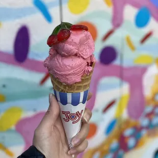 Strawberry shortcake on a waffle cone. One scoop