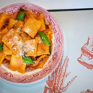 a bowl of pasta with a skull in the background