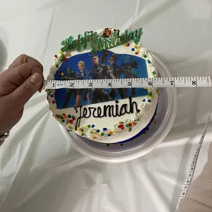 a person measuring a birthday cake