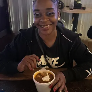 a woman sitting at a table with a cup of hot chocolate