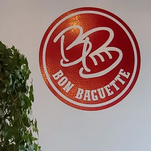 a plant in front of a bon baguette sign
