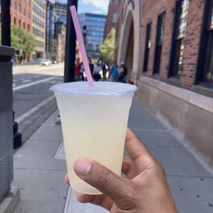 a hand holding a plastic cup with a pink straw