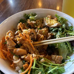 a bowl of asian food with chopsticks