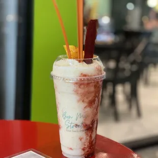a drink in a plastic cup with a straw and a stick sticking out of it