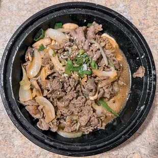 beef and onions in a black bowl