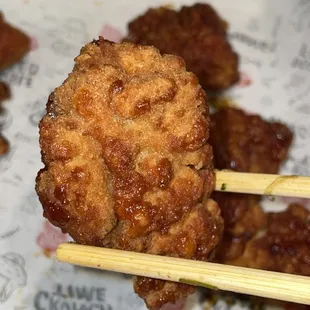 a close up of a fried food item with chopsticks