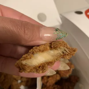 a hand holding a piece of fried food