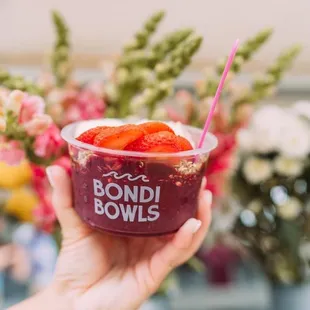 a hand holding a bowl of fruit
