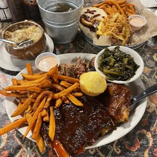 ows a plate of ribs, french fries, coleslaw, and a side of greens