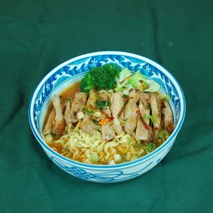a blue and white bowl filled with noodles and meat