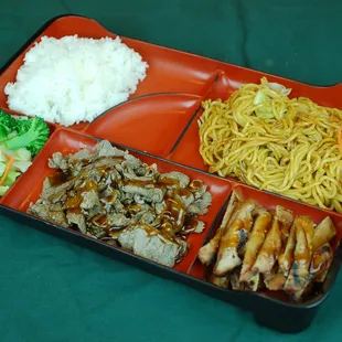a tray of food with rice, meat, and vegetables