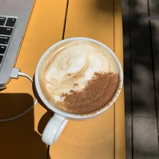 a cup of cappuccino and a laptop