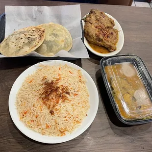 a plate of rice, a plate of chicken and a plate of bread