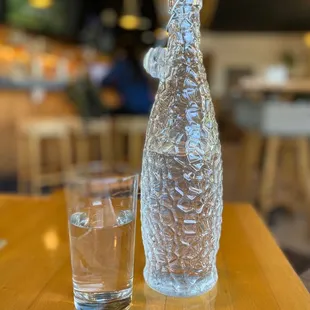 a glass of water and a bottle on a table
