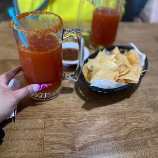 a person holding a drink and chips