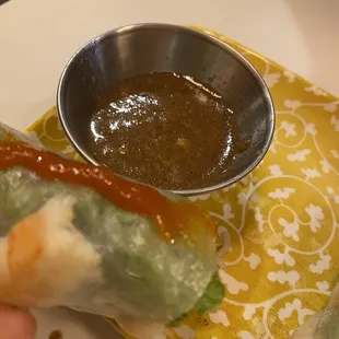 a hand holding a roll with dipping sauce