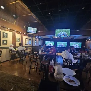 people sitting at tables watching tvs