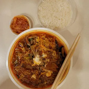 a bowl of stew, rice, and chopsticks