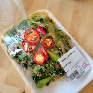 a plastic container with a salad wrapped in plastic