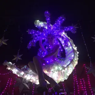 a woman sitting on a bed covered in lights