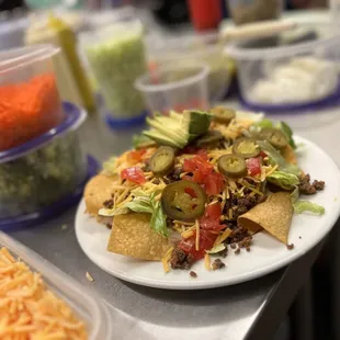 a plate of nachos with cheese, tomatoes, and lettuce