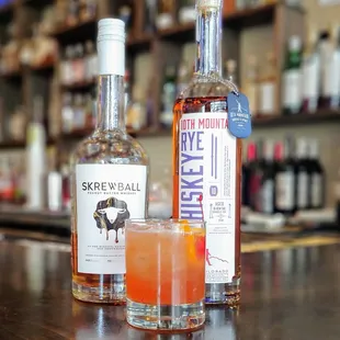 a bottle of skrewball and a glass of whiskey