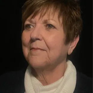 a woman with short hair and a white sweater