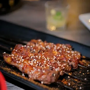 a steak on a grill with sesame sprinkled on top