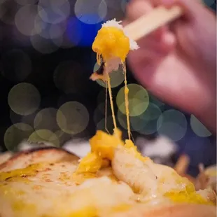 a person holding a piece of cheese on a fork