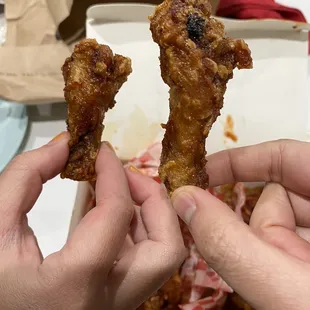 two hands holding a piece of fried chicken