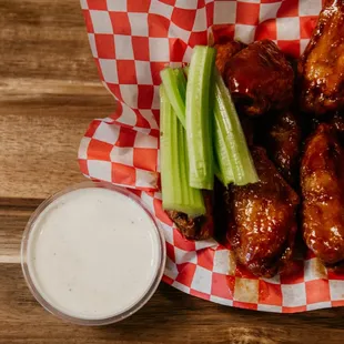 a basket of wings, celery, and ranch dressing