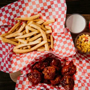 a tray of chicken wings, fries, corn, and a drink