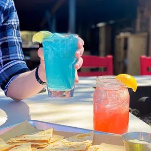 a person holding a drink and a plate of tortillas