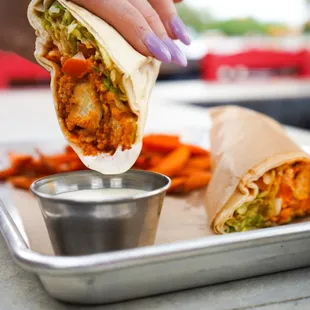 a hand dipping a burrito