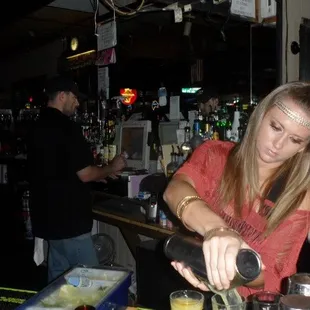 a woman pouring a drink at a bar