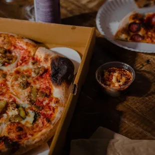 a pizza in a box and a glass of wine